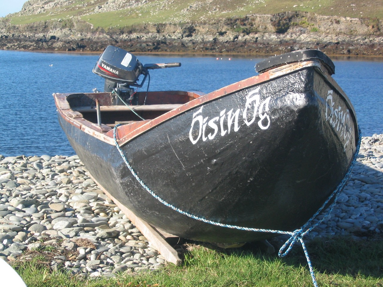 Currach sitting on the the barrier of stones diving Lough Bofin from the sea.